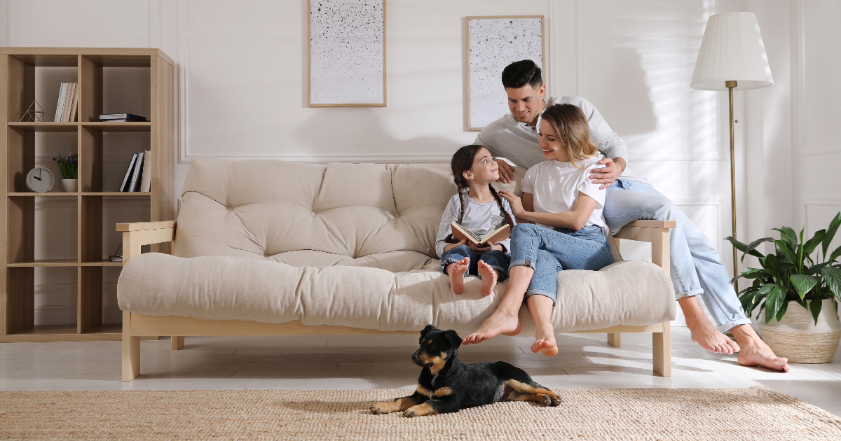Family and pooch sat on sofa looking happy
